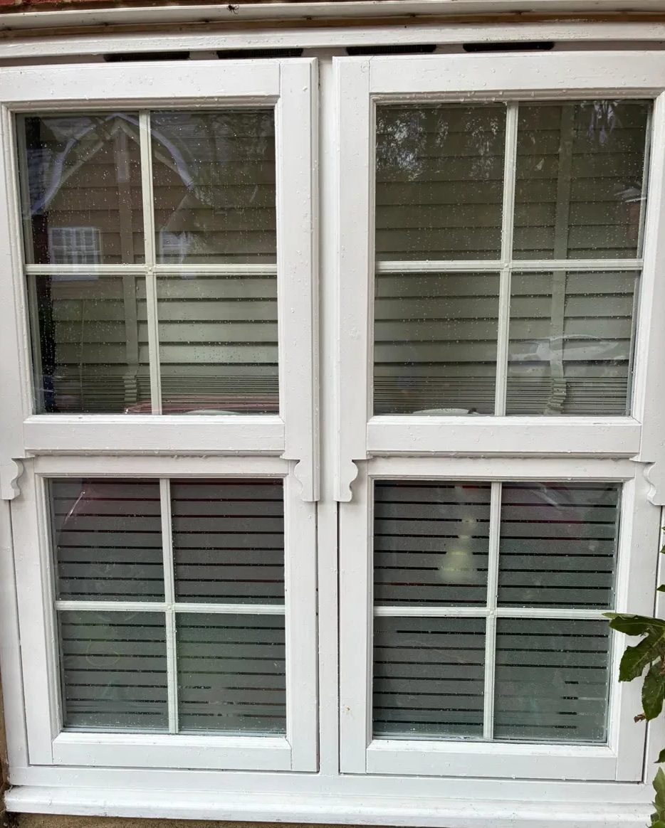 After the clean: the same white window with clear glass and clean frames and sills, still wet from the pure water rinse